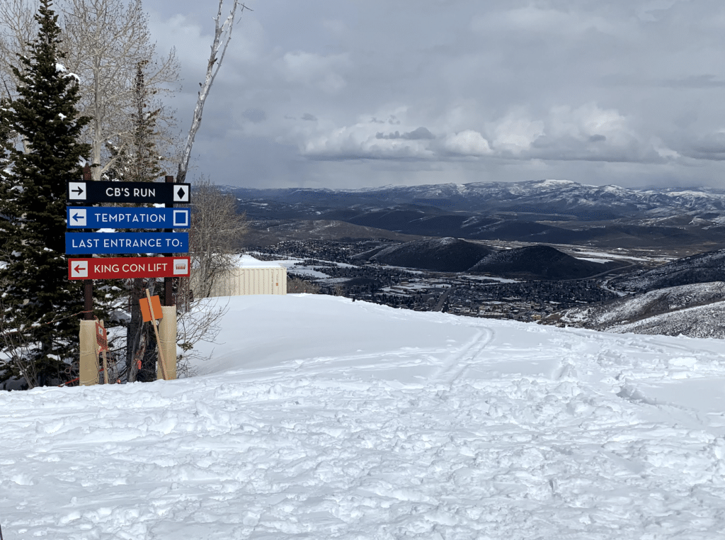 Trail signs for CB's Run, Temptation and King Con lift at Park City Mountain with Park City below