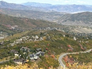 Fall colors on the hillsides above Deer Valley East Village homes and a winding mountain road near Park City, Utah