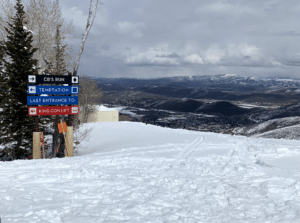 Trail signs for CB's Run, Temptation and King Con lift at Park City Mountain with Park City below